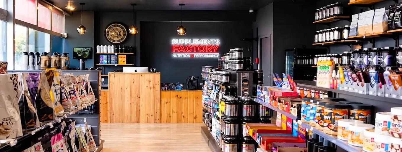Intérieur de la boutique Supplements Factory à Seysses avec enseigne lumineuse et rayons de compléments